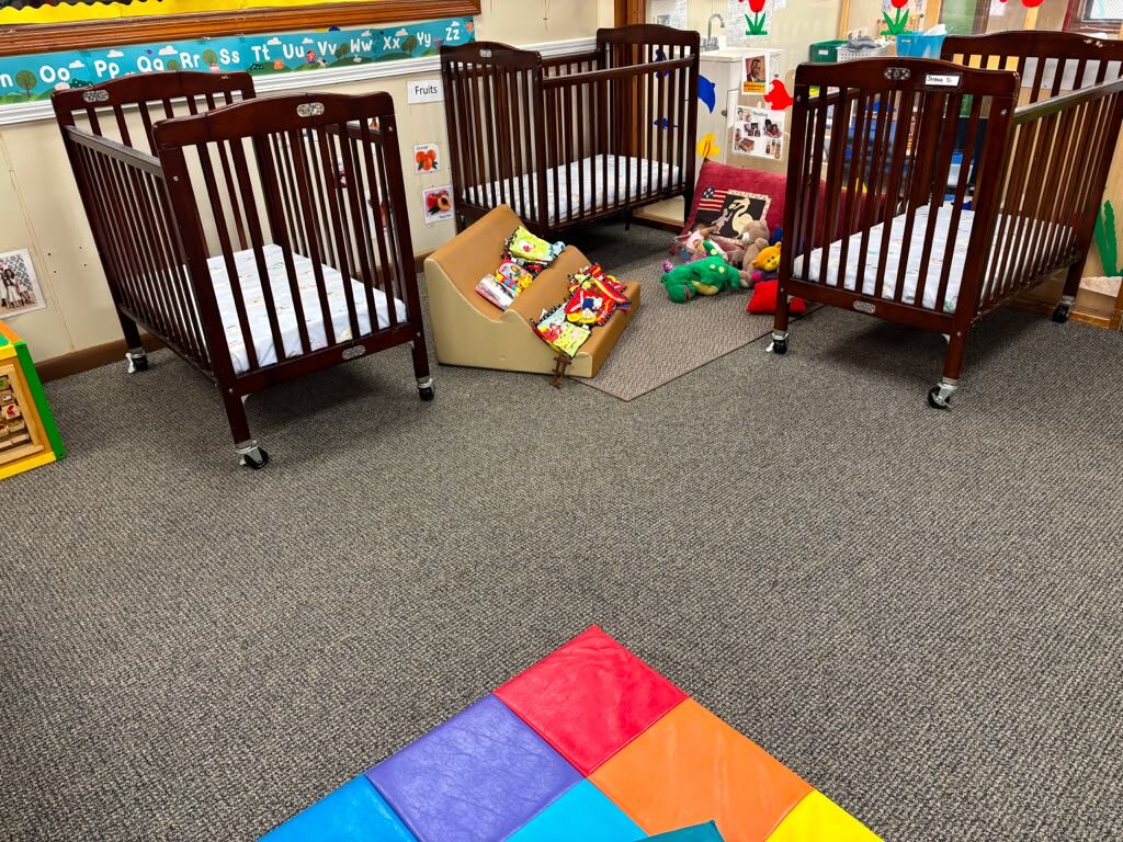 Infant nursery with cribs and alphabet wall at Marietta Academy in Marietta, GA
