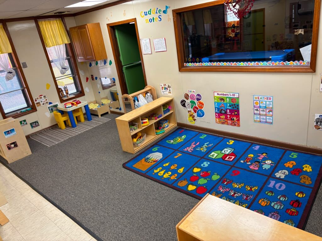 Toddler classroom with Numbers 1-10 rug, weather chart, and colors display at Marietta Academy