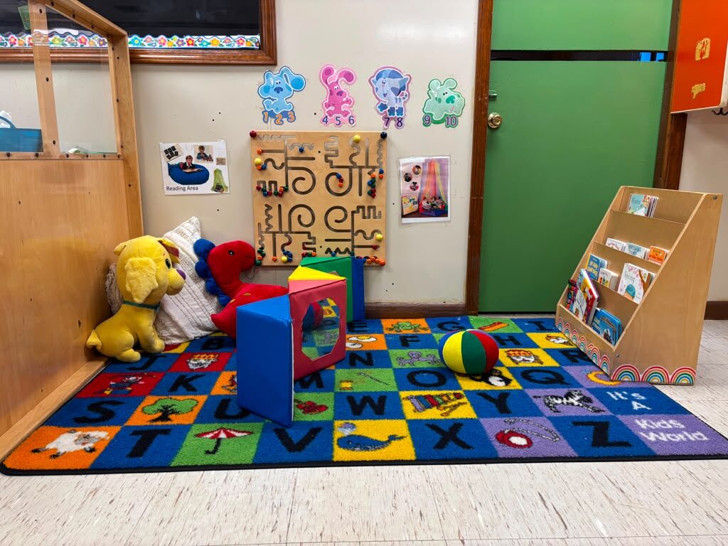 Cozy reading area with alphabet rug and books at Marietta Academy